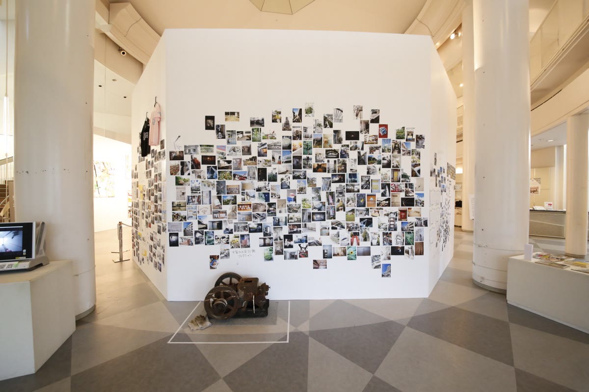 Des photographies couvrant un mur blanc, un moniteur posé au sol