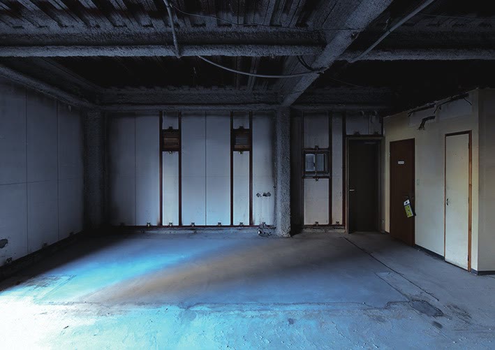 Un interior de hormigón con azul y marrón extendidos por el suelo y puertas a la derecha